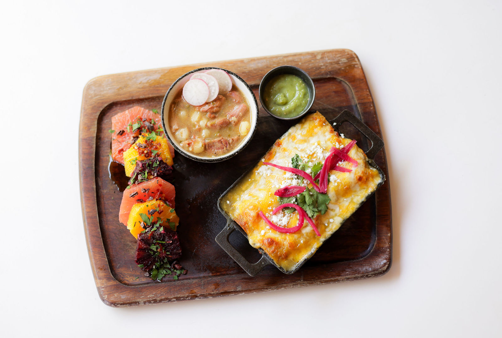 The Southwest board: a cheese enchilada in cast iron, green chili pork stew with radish, citrus and salmon salad, and salsa verde