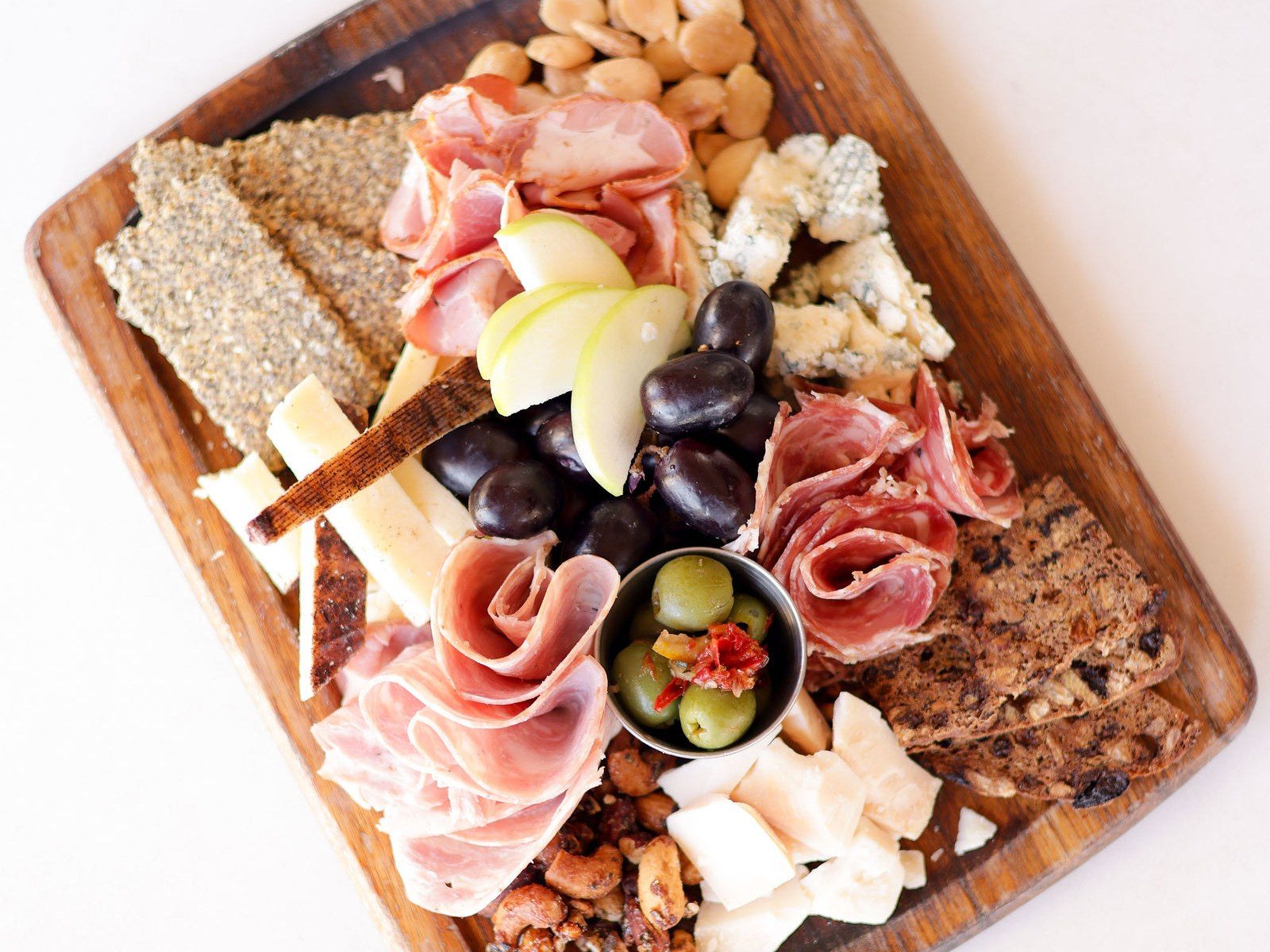 Cheese + Charcuterie Board — hard + soft cheeses, charcuterie, fruit, nuts, spicy castelvetrano olives, gf house made seeded