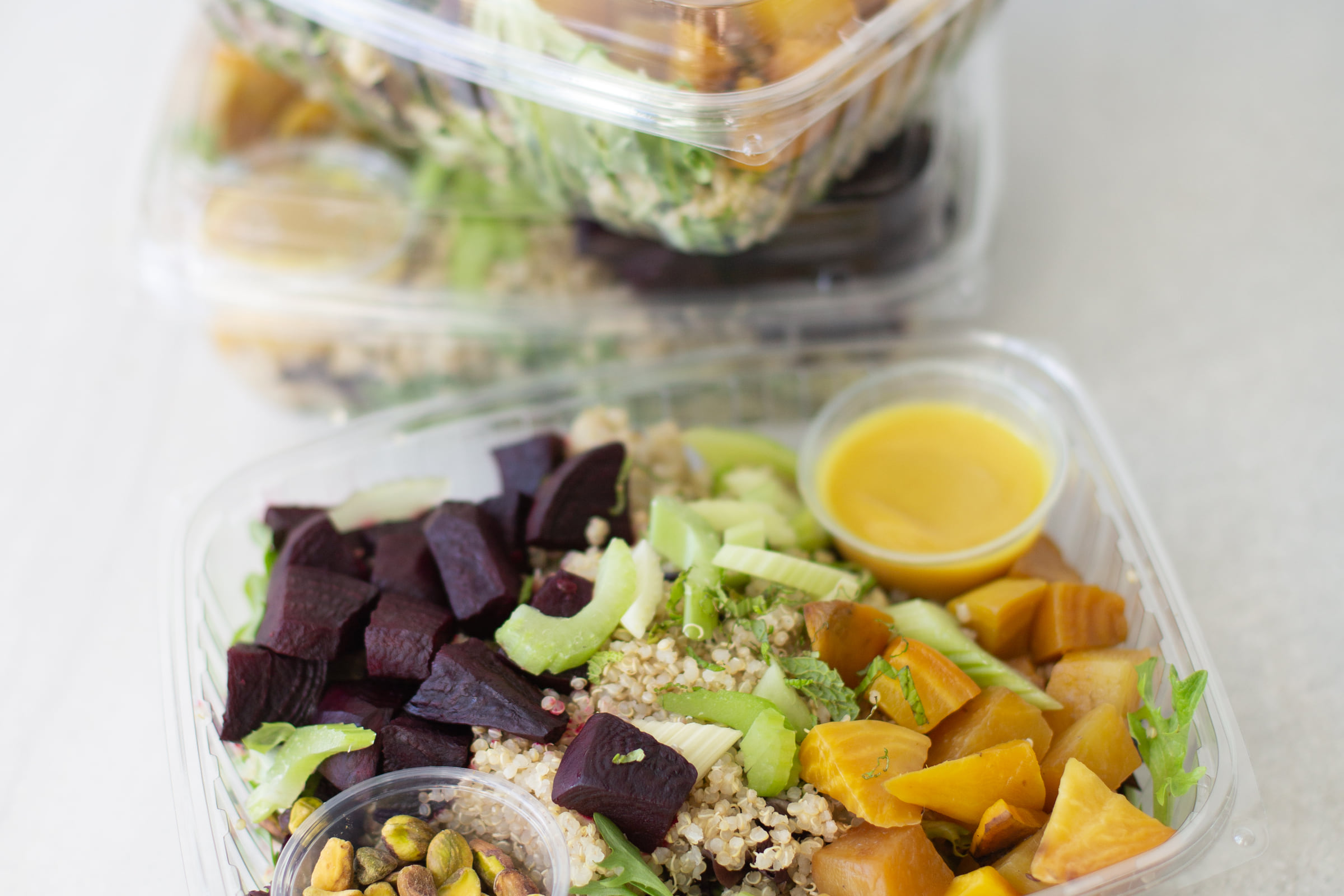 Packaged salads of quinoa with roasted red and golden beets, celery and mint, each with a cup of dressing and one of pistachios