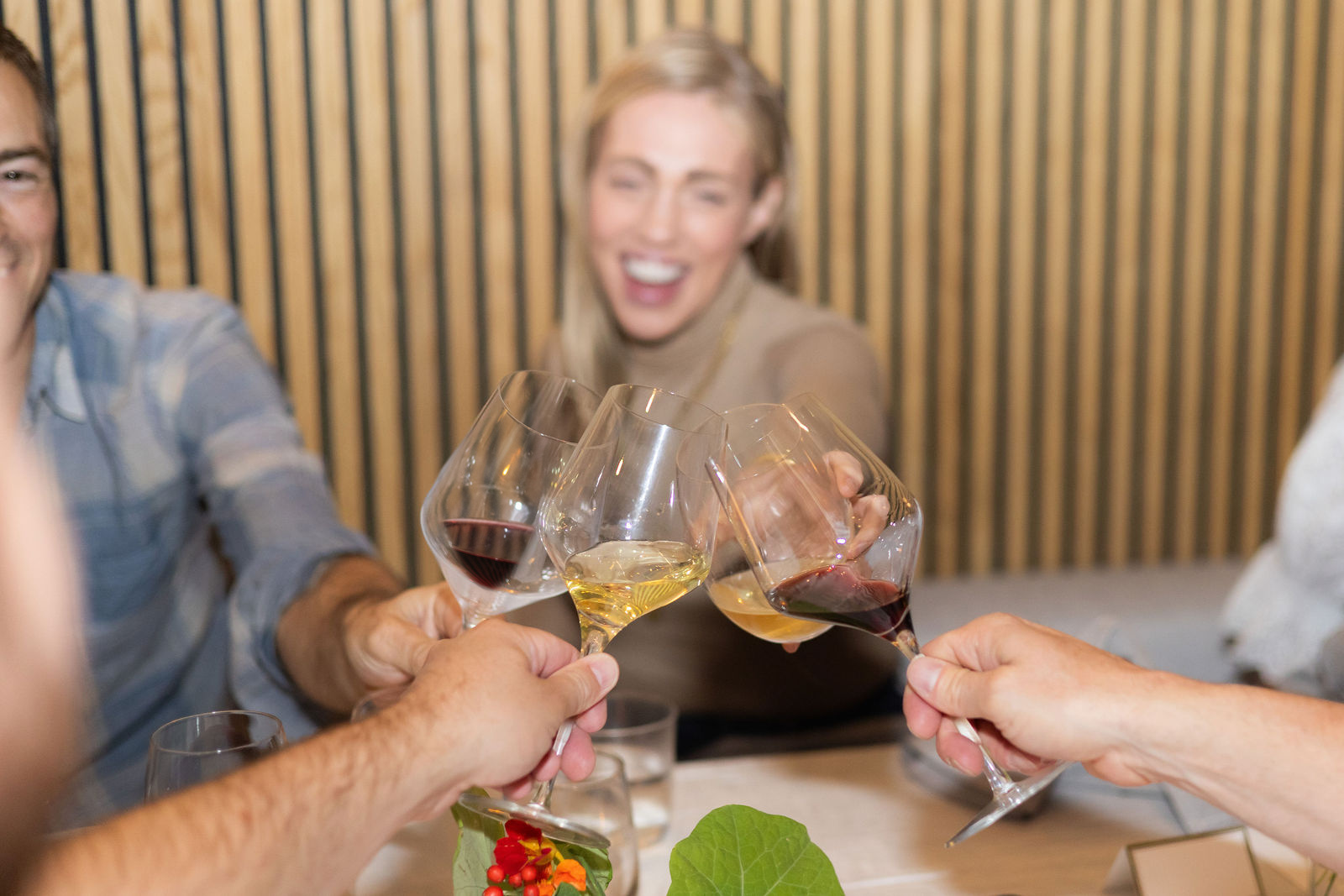 Guests clinking glasses across a table, red and white in hand.