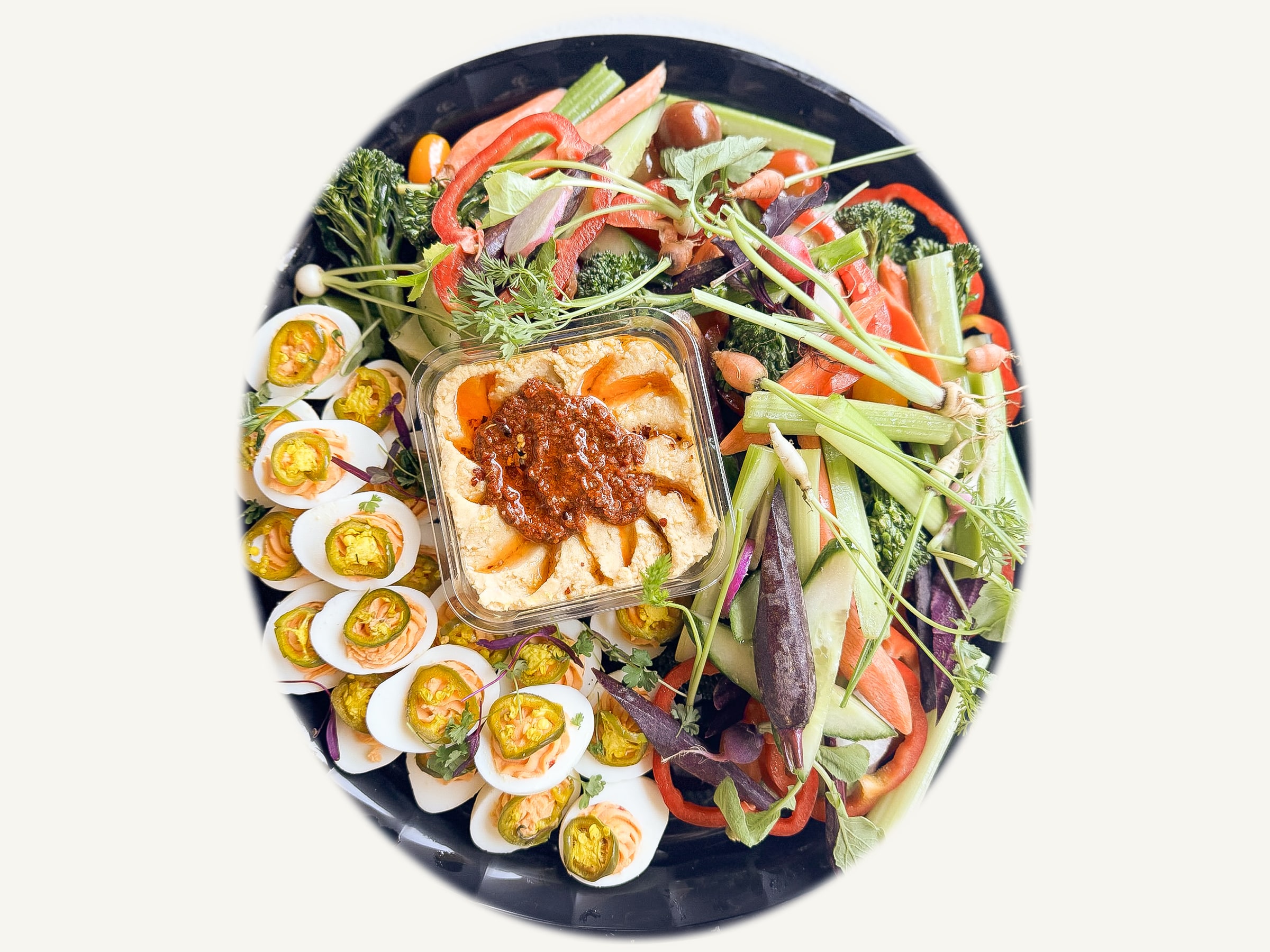 An Amelia&rsquo;s party platter: crudit&eacute;s, spicy deviled eggs and hummus topped with calabrian relish on a black tray